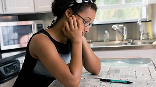 Woman looks at financial pages in the newspaper.